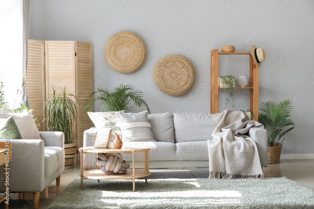 Interior of light living room with sofas, houseplants and table