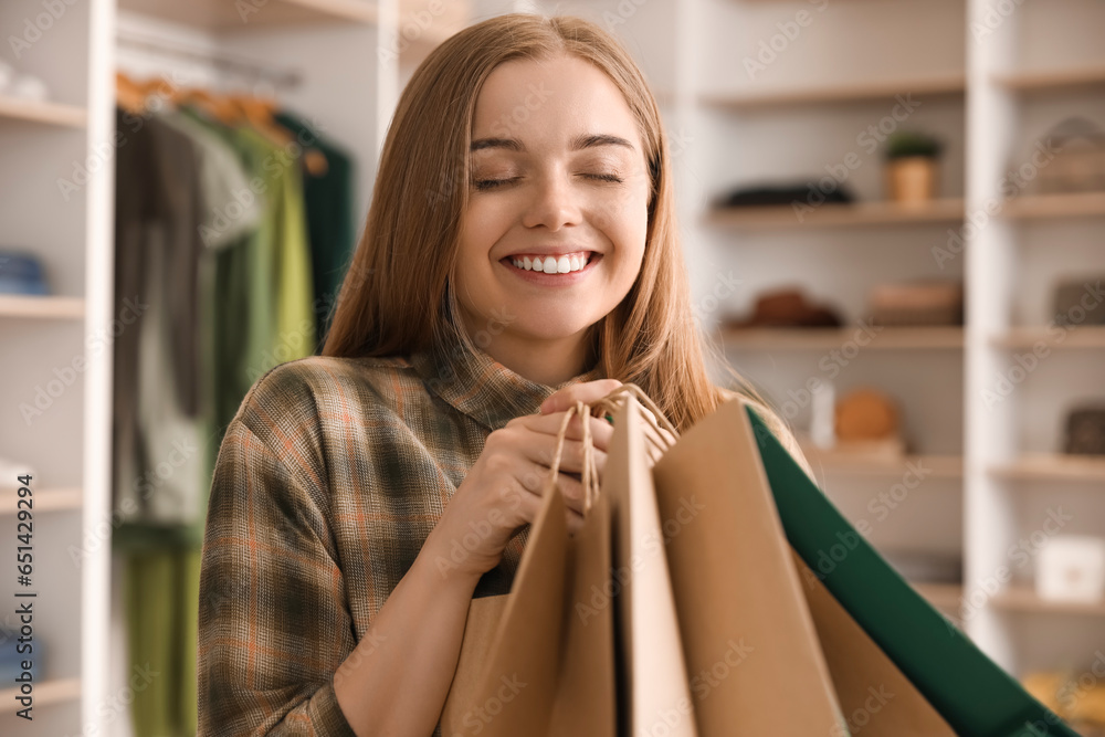 Happy young woman with shopping bags in boutique