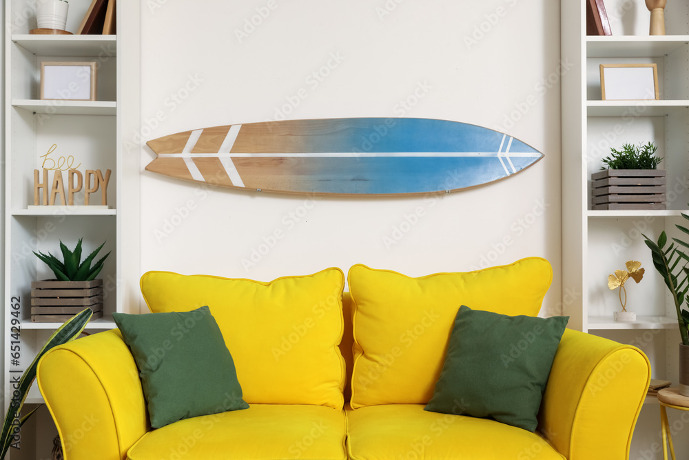 Interior of light living room with surfboard and yellow sofa