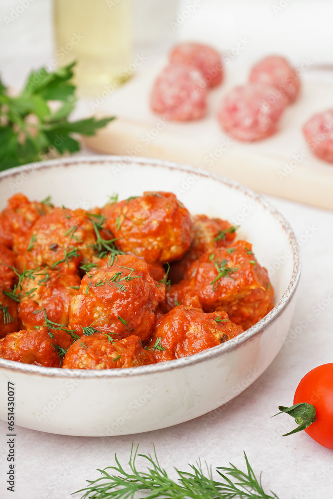 Bowl of tasty meat balls with sauce on light background