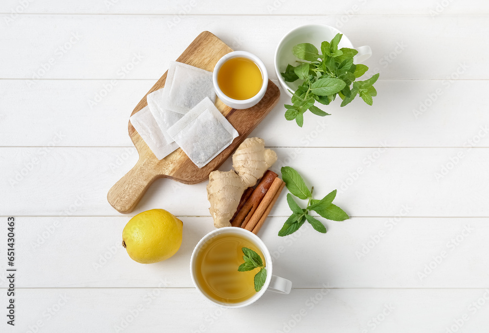 Cup of fresh mint tea with ginger root, lemon, honey and cinnamon on white wooden table