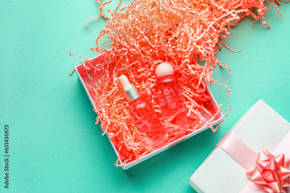 Opened gift box with cosmetics and packing paper on turquoise background