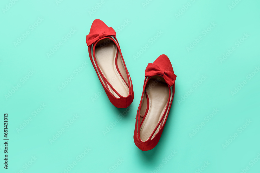 Pair of red shoes with bow on turquoise background