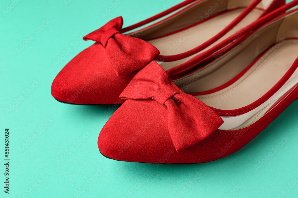 Pair of red shoes with bow on turquoise background