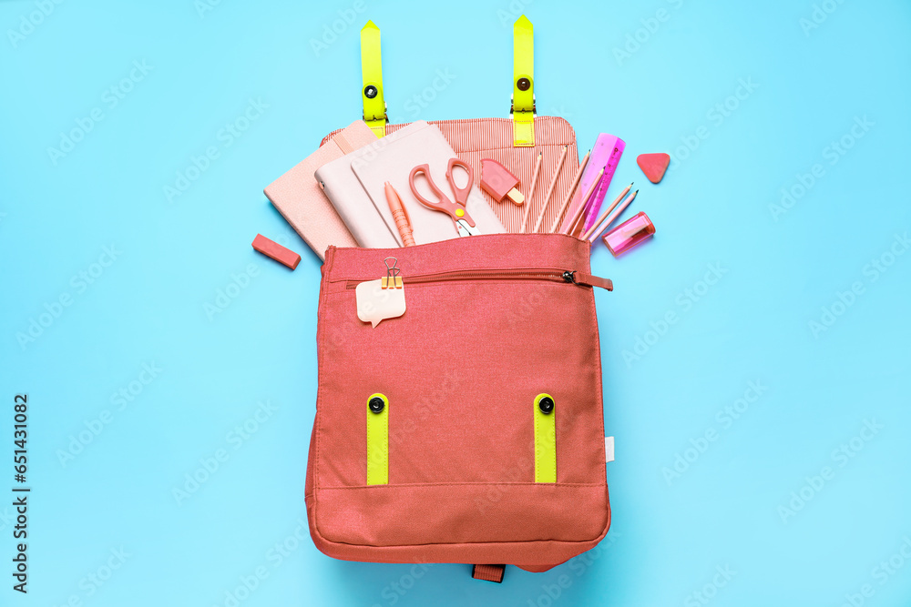 Pink school bag with stationery on blue background