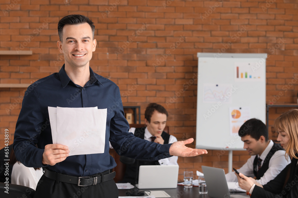 Male business consultant with papers working in office