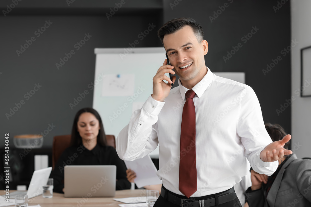 Male business consultant talking by mobile phone in office