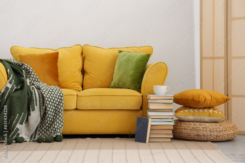 Yellow sofa with plaid in interior of living room