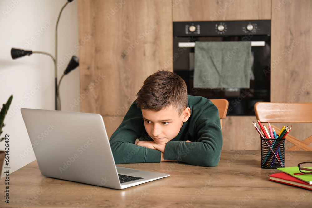 Little boy studying online with laptop in kitchen