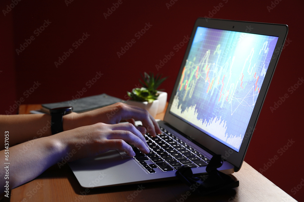 Female programmer typing on laptop keyboard at night in office, closeup