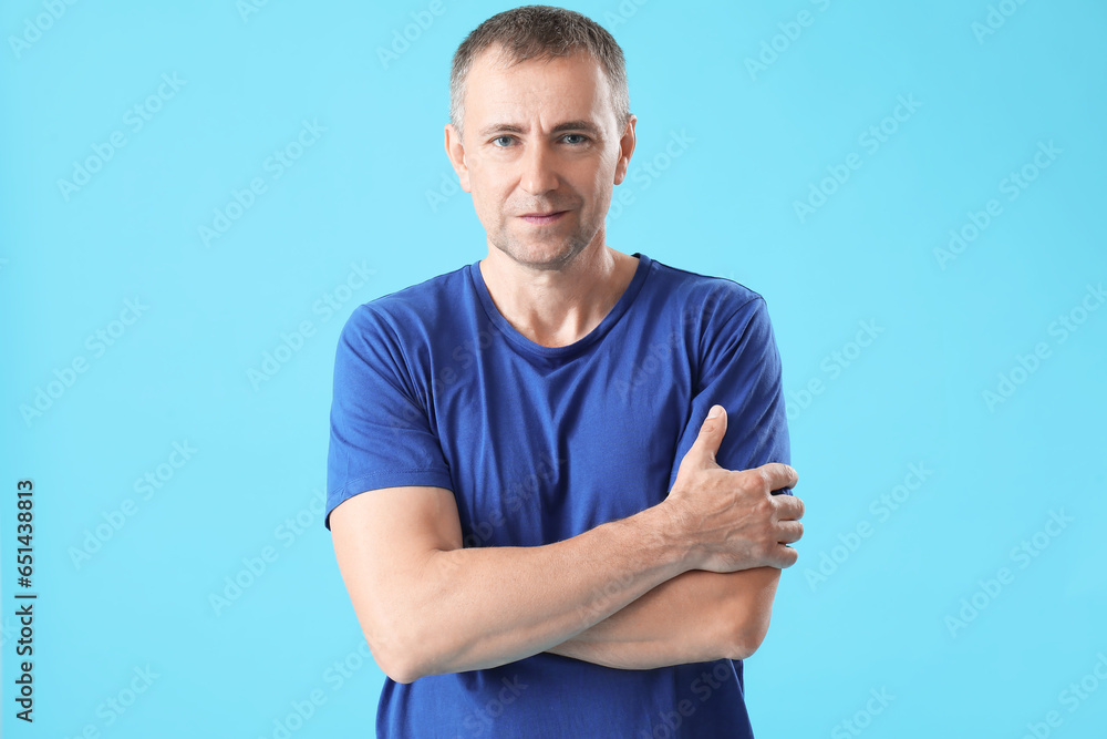 Portrait of handsome mature man with crossed arms on blue background