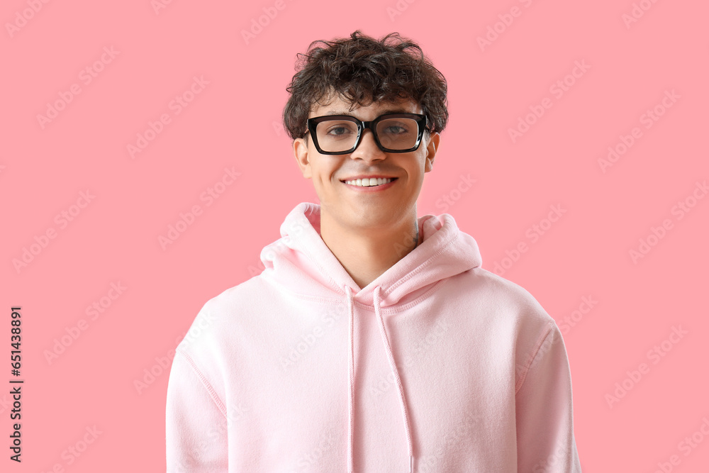 Portrait of handsome young man in eyeglasses on pink background