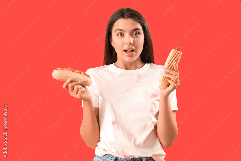 Surprised young woman with different hot dogs on red background