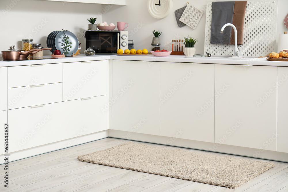 Interior of modern kitchen with stylish rug and white counters