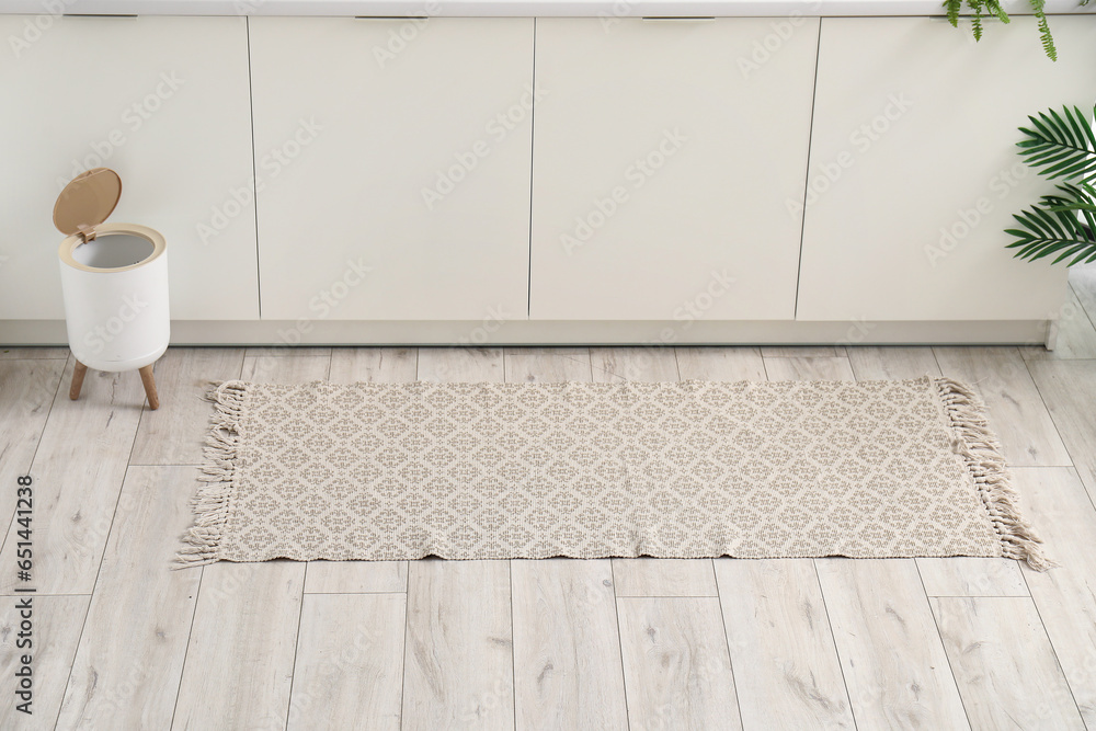 Stylish rug and trash bin on floor in kitchen