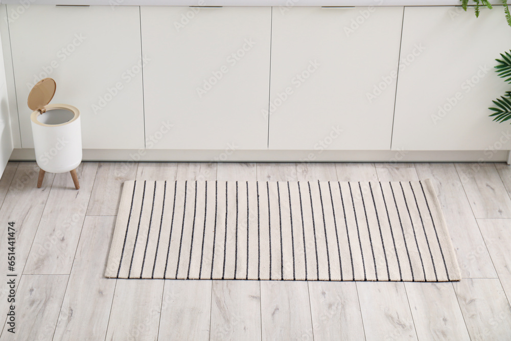 Stylish rug and trash bin on floor in kitchen