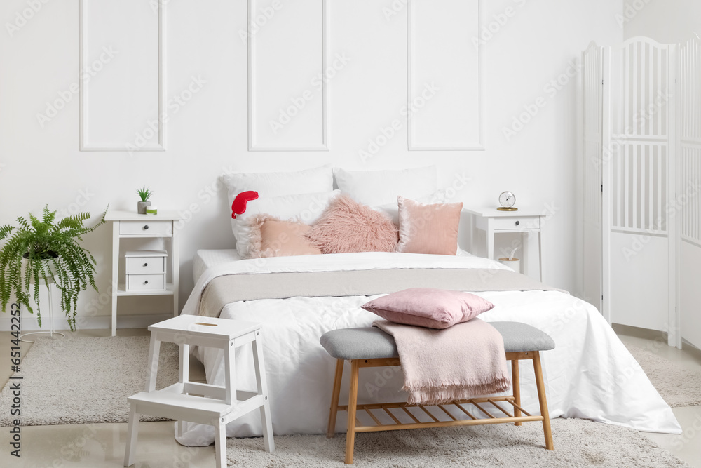 Interior of light bedroom with tables and soft bench