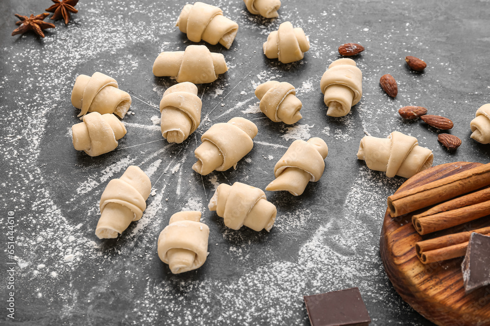 Composition with raw croissants and flour on dark background