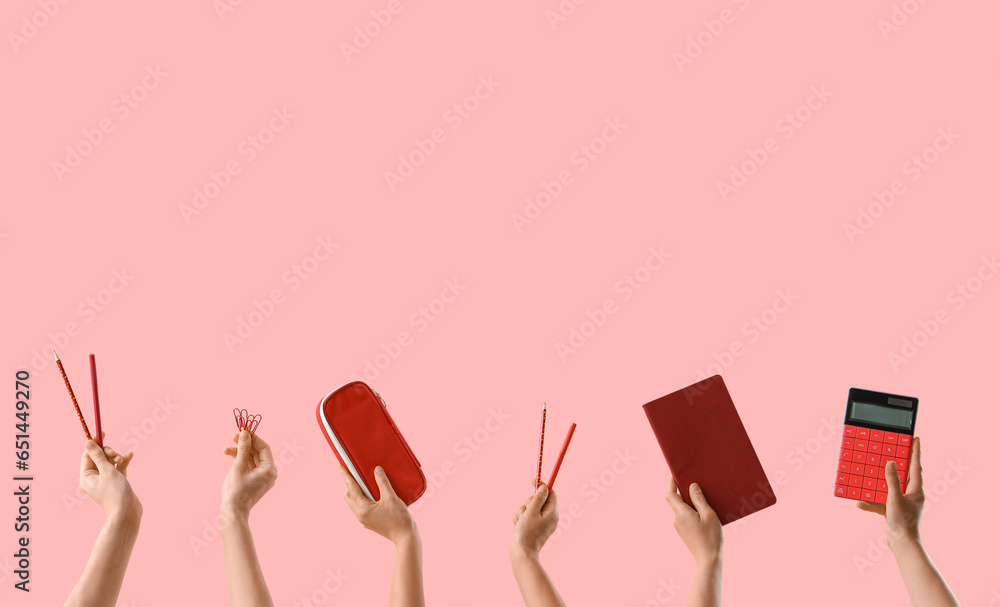 Many hands with school supplies on pink background