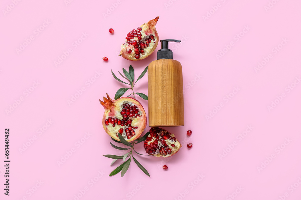 Composition with bottle of cosmetic product and ripe pomegranate on pink background