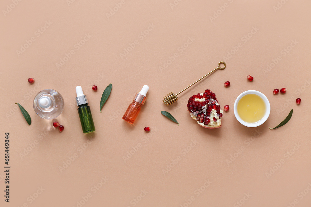 Composition with bottles of essential oil, honey and pomegranate on color background