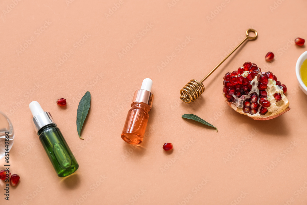 Composition with bottles of essential oil, honey dipper and pomegranate on color background