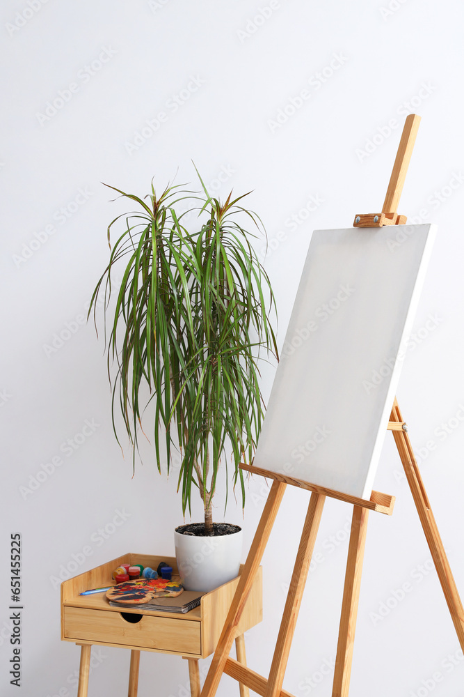 Wooden easel with blank canvas near grey wall