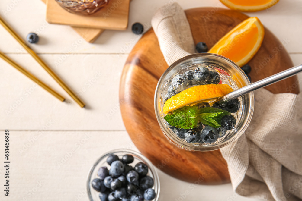 Glass of fresh blueberry lemonade with orange on white wooden table