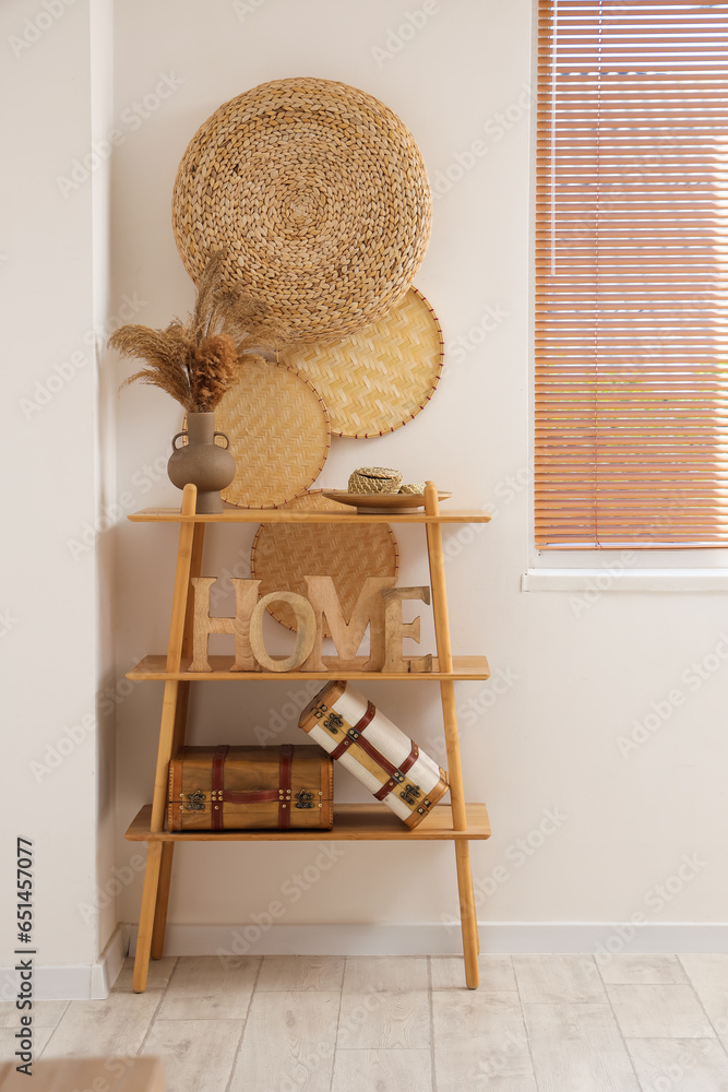 Wooden shelving unit with decor near white wall