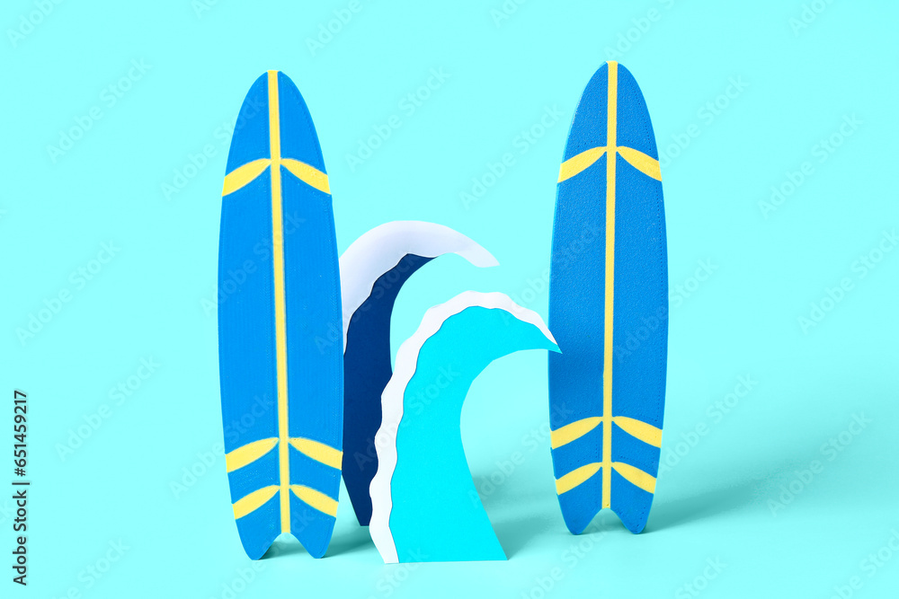 Creative composition with paper waves and mini surfboards on blue background