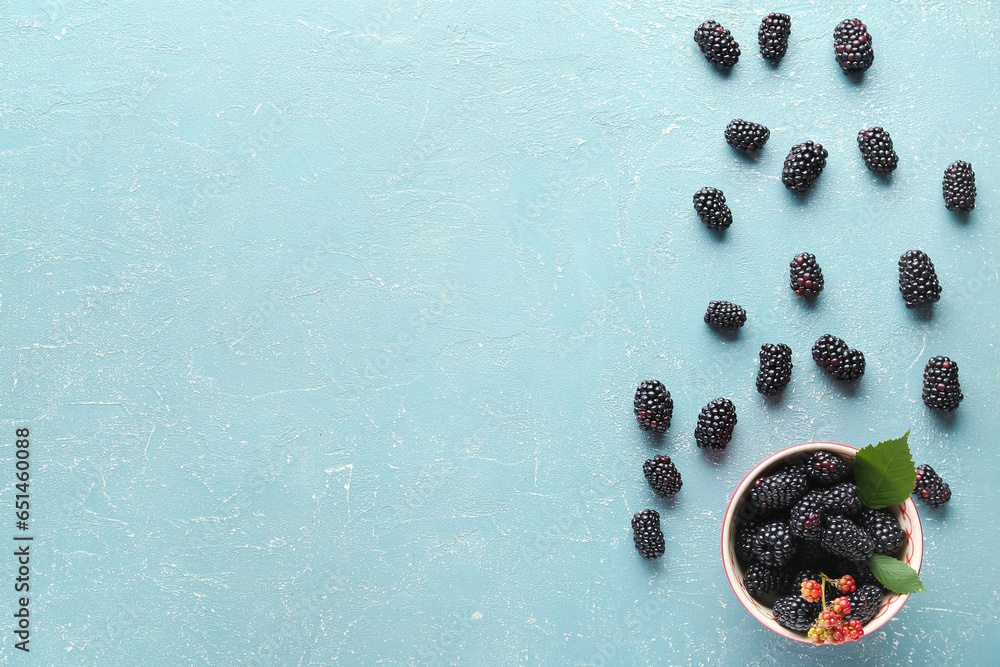 Bowl with fresh blackberries on blue background