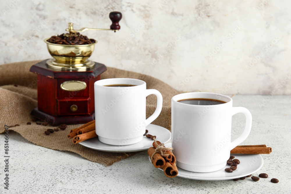 Cups of tasty coffee with cinnamon on light background