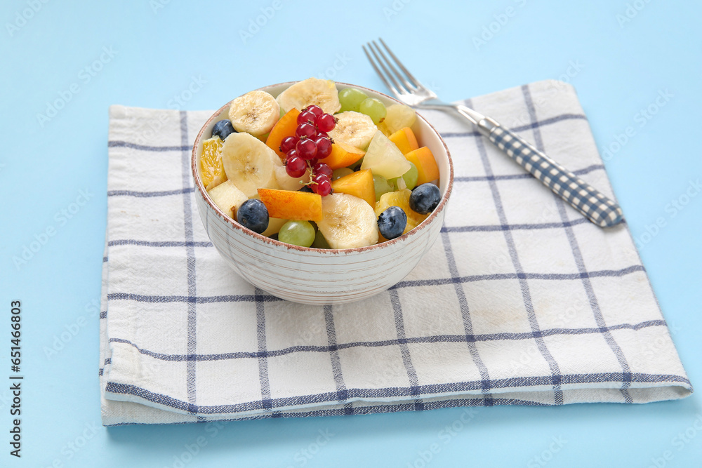 Bowl with fresh fruit salad on blue background