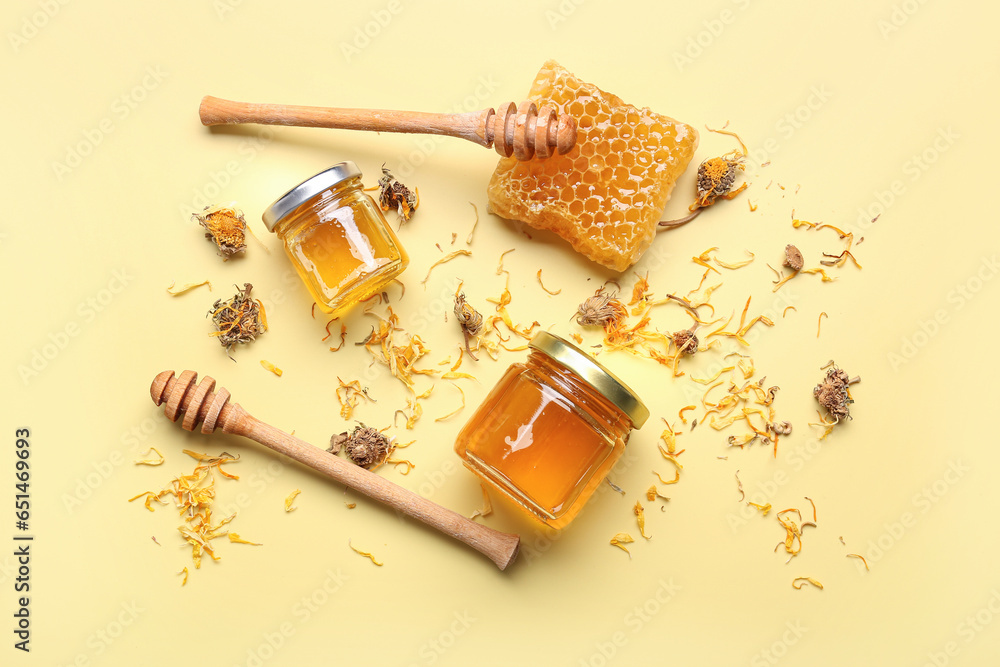 Jars with tasty honey, honeycomb, dippers and dried dandelion flowers on beige background