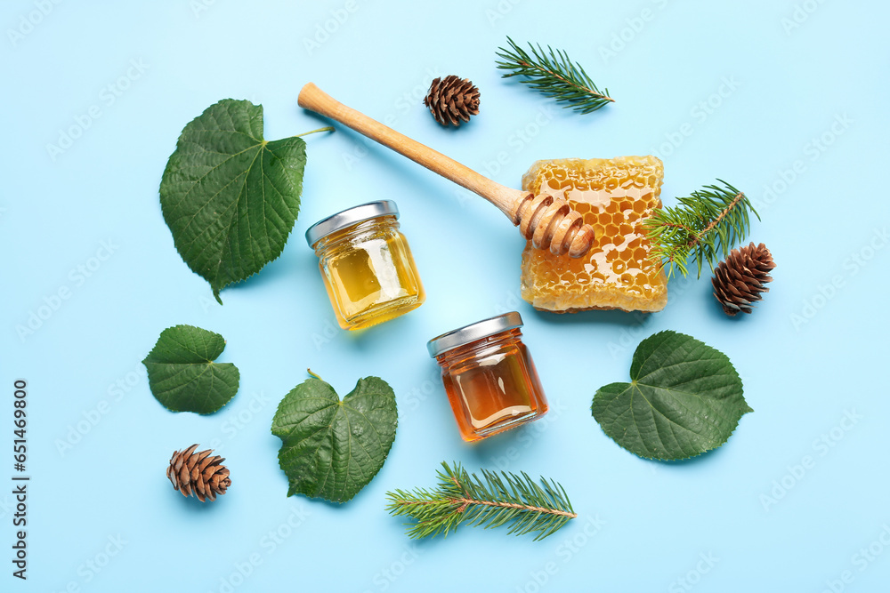 Composition with tasty honey, honeycomb, dipper, fir tree branches and green leaves on blue background