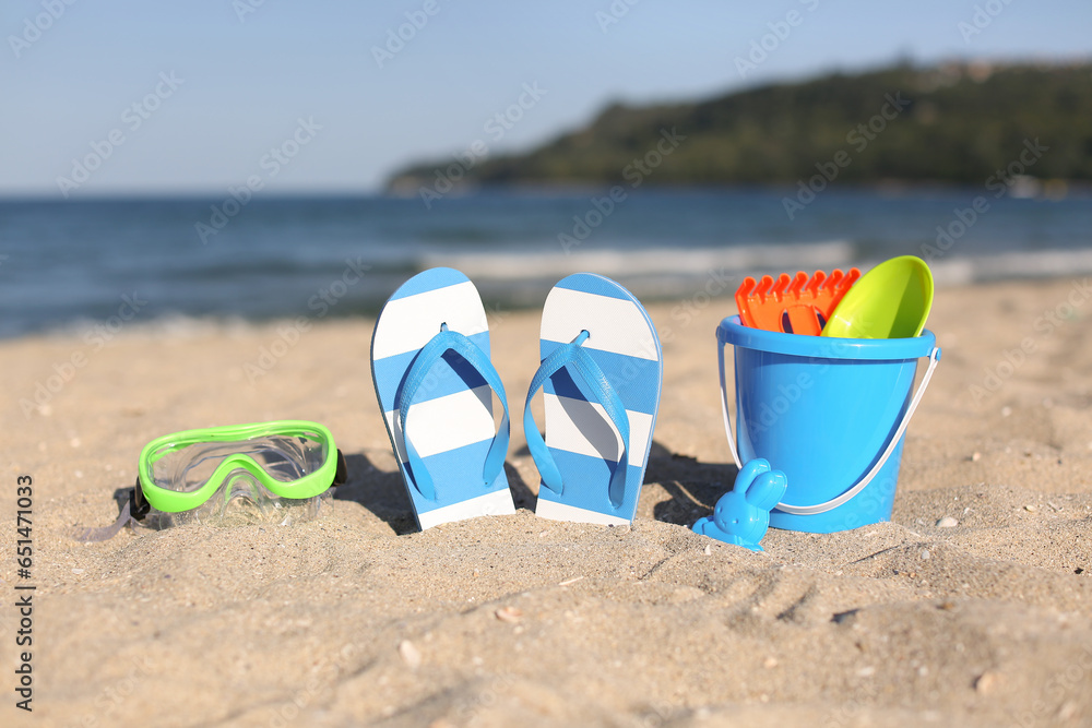 Stylish female blue flip flops, snorkeling mask and beach accessories for children on sand