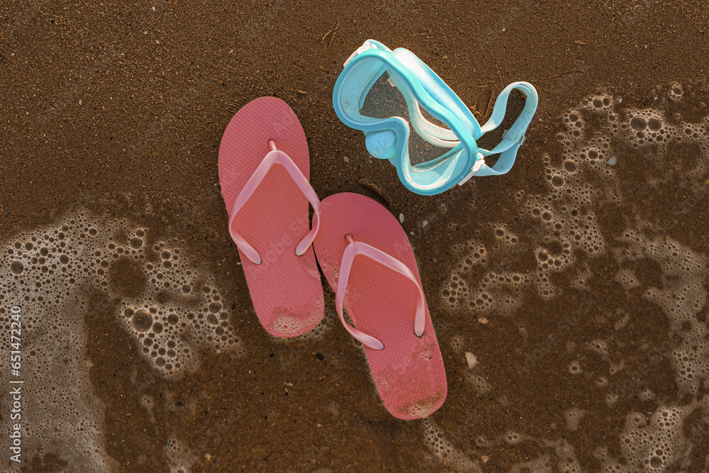 Stylish female flip flops and snorkeling mask on sea shore