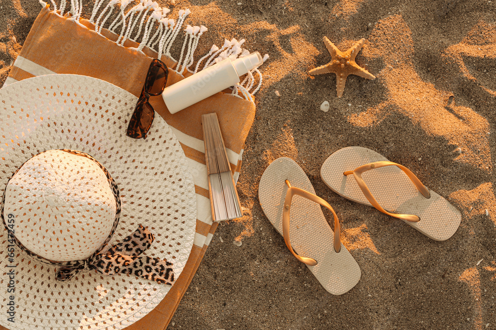 Stylish female flip flops and beach accessories on sand