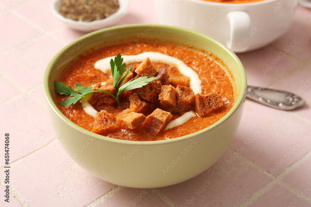 Bowl of tasty cream soup with croutons on pink tile background