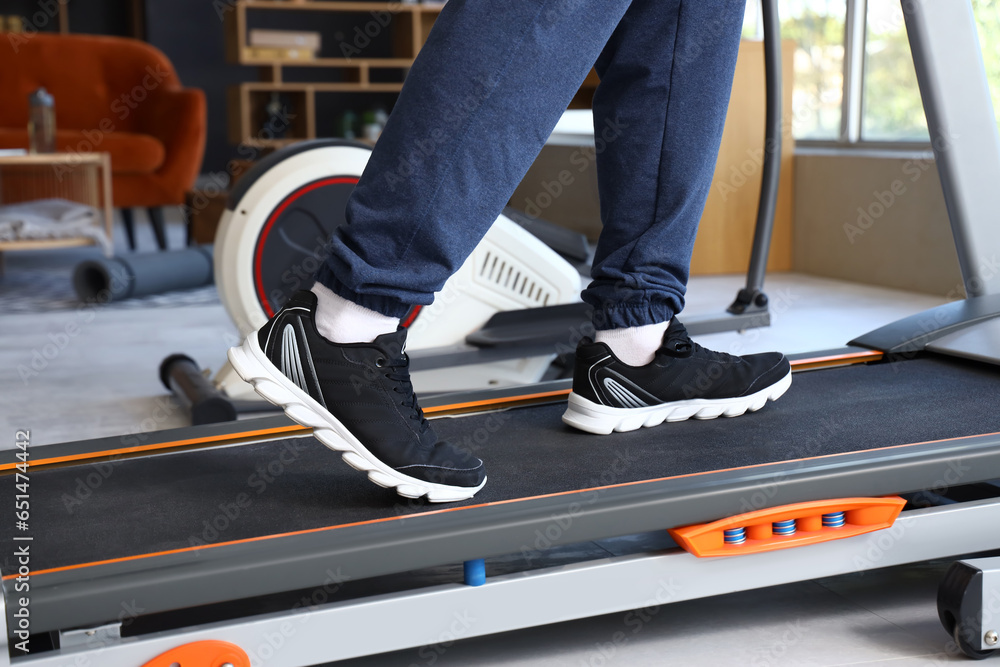 Sporty mature man training on treadmill at home, closeup