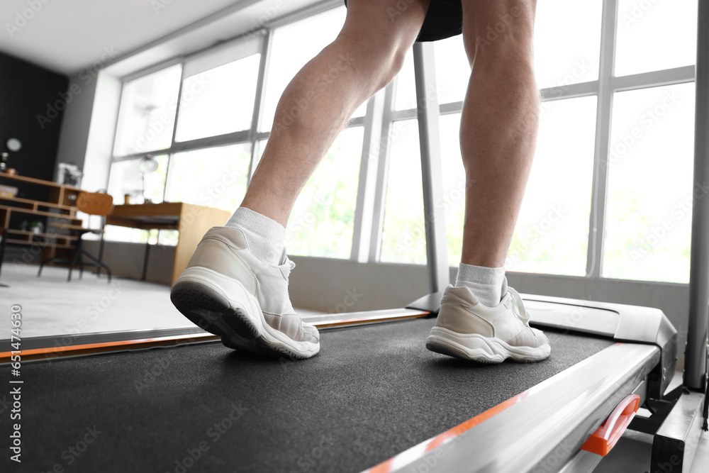 Sporty mature man training on treadmill at home, closeup