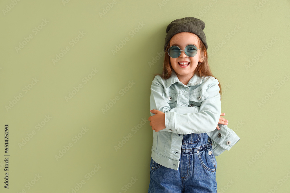 Cute little girl in sunglasses on green background