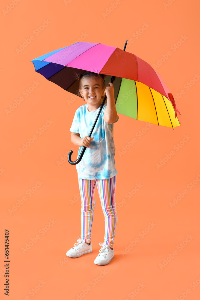 Cute little girl with umbrella on orange background