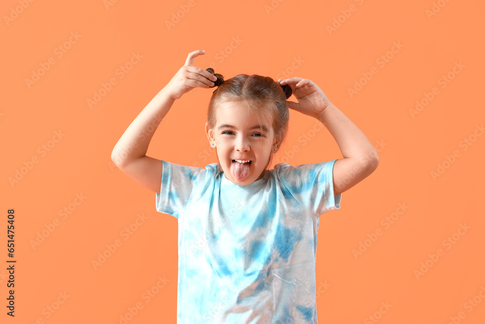 Cute little girl showing tongue on orange background