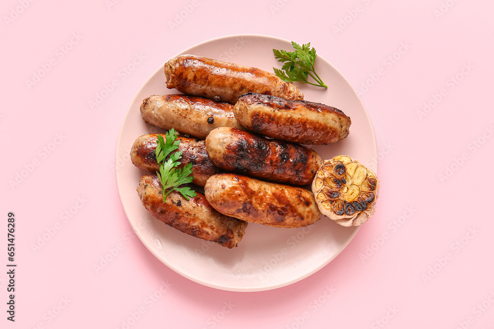 Plate of tasty grilled sausages on pink background