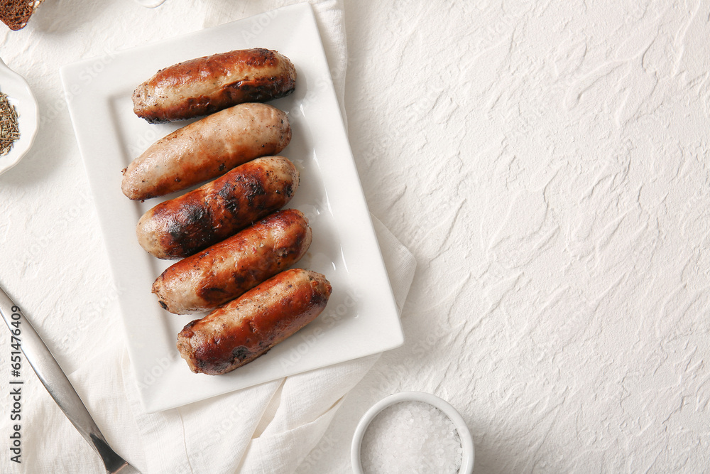 Plate of tasty grilled sausages on white background