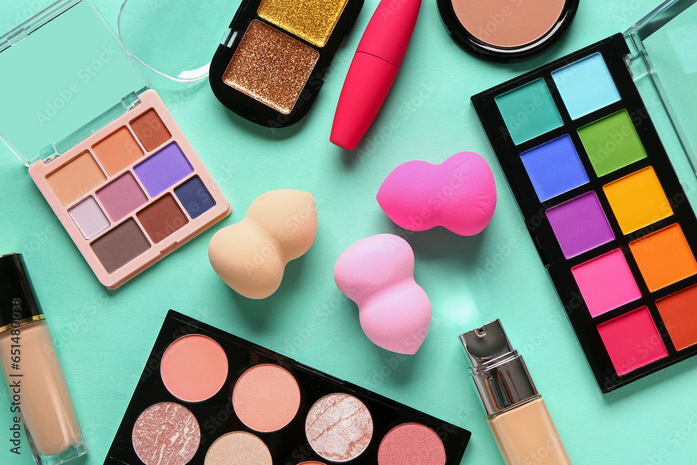 Composition with different cosmetic products and makeup sponges on color background