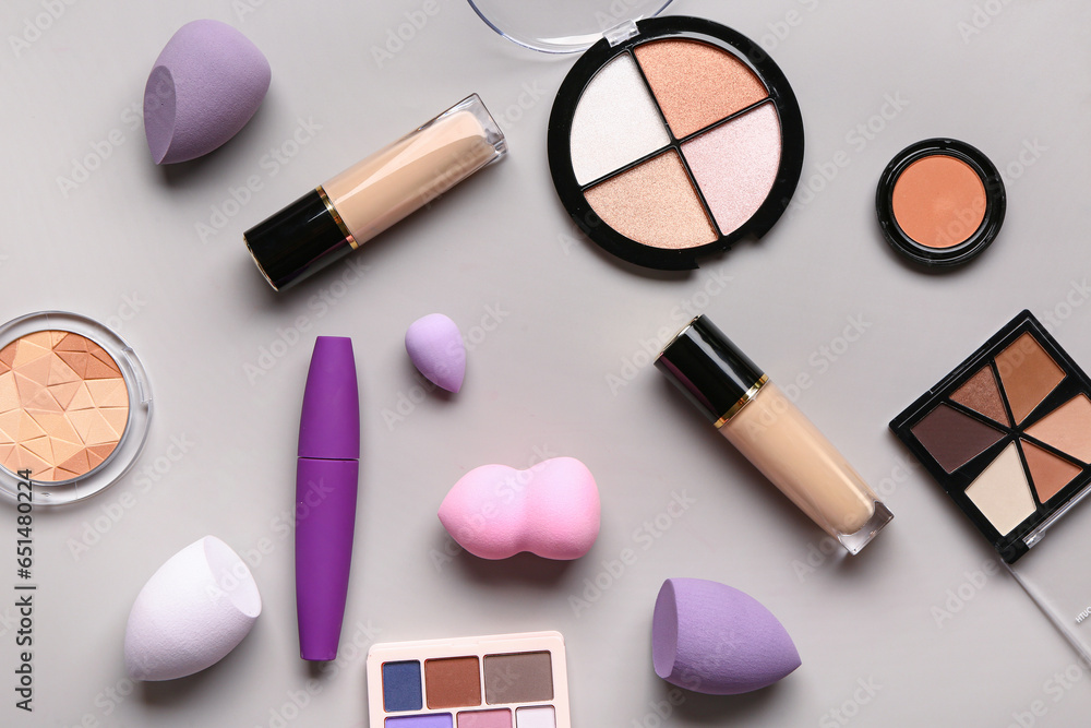 Composition with different makeup sponges and decorative cosmetics on grey background