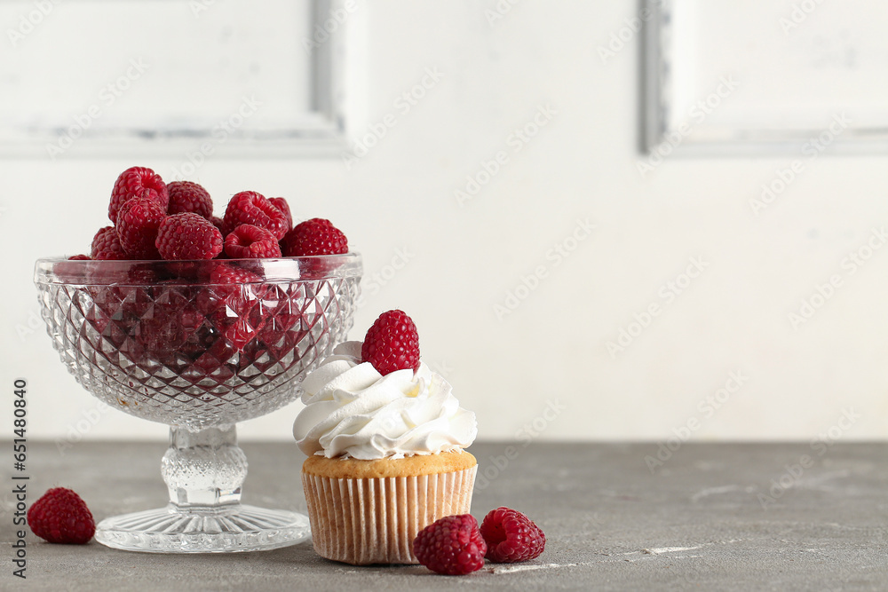 Tasty raspberry cupcakes and bowl with fresh berries on table