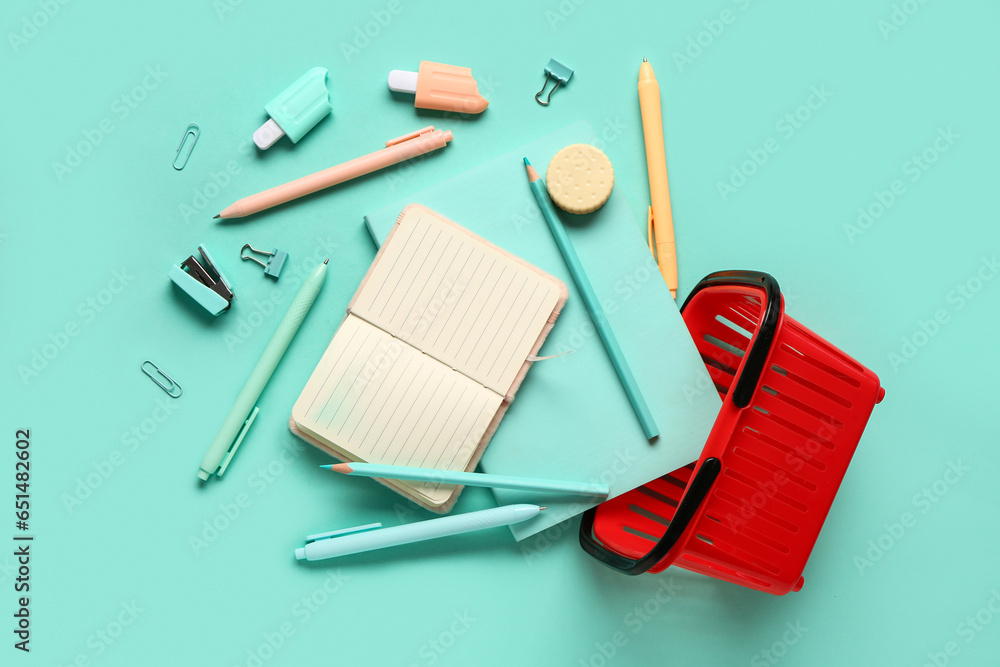 Composition with shopping basket and different stationery on turquoise background